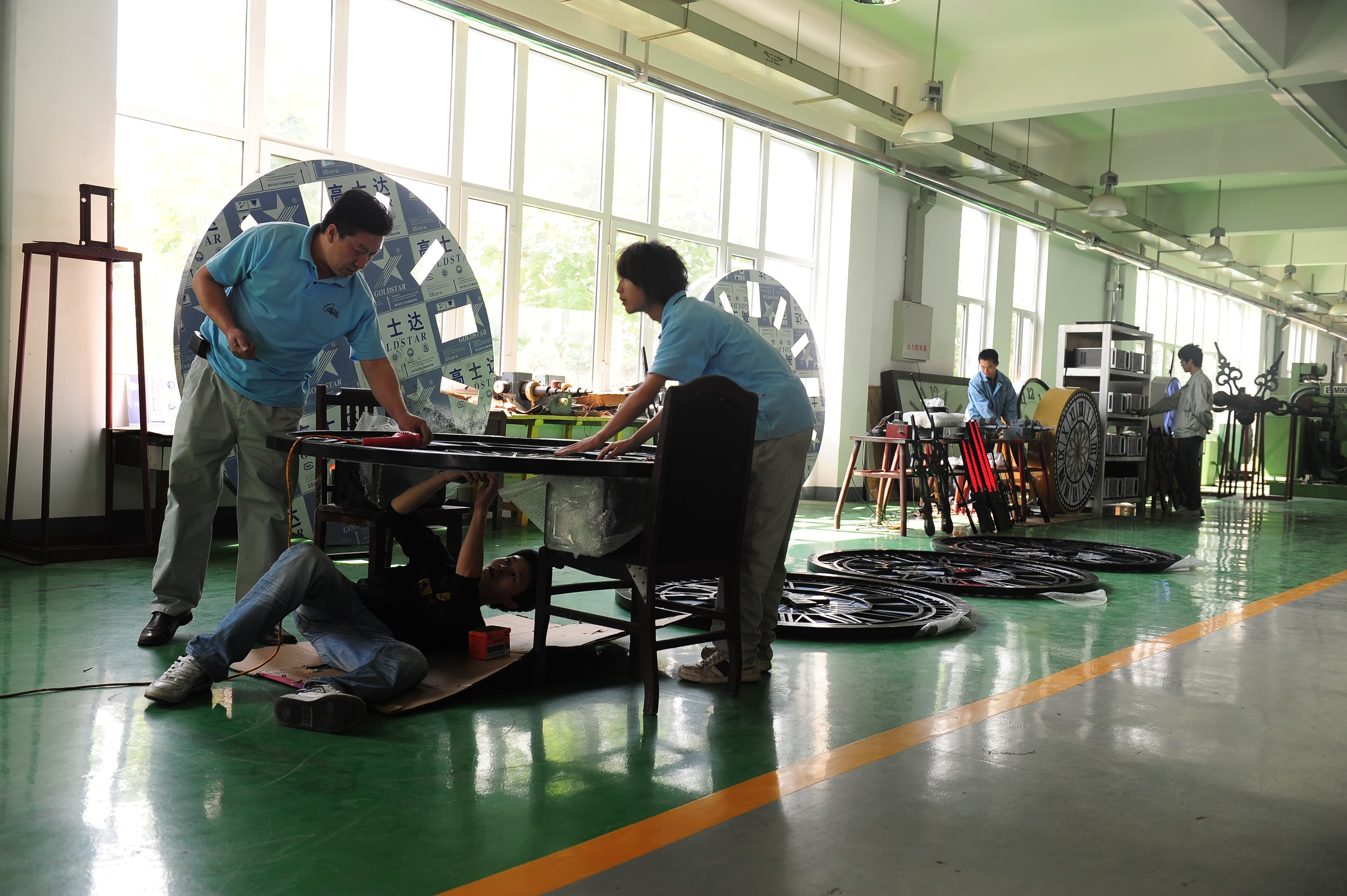Factory team assembling clock components and frames.