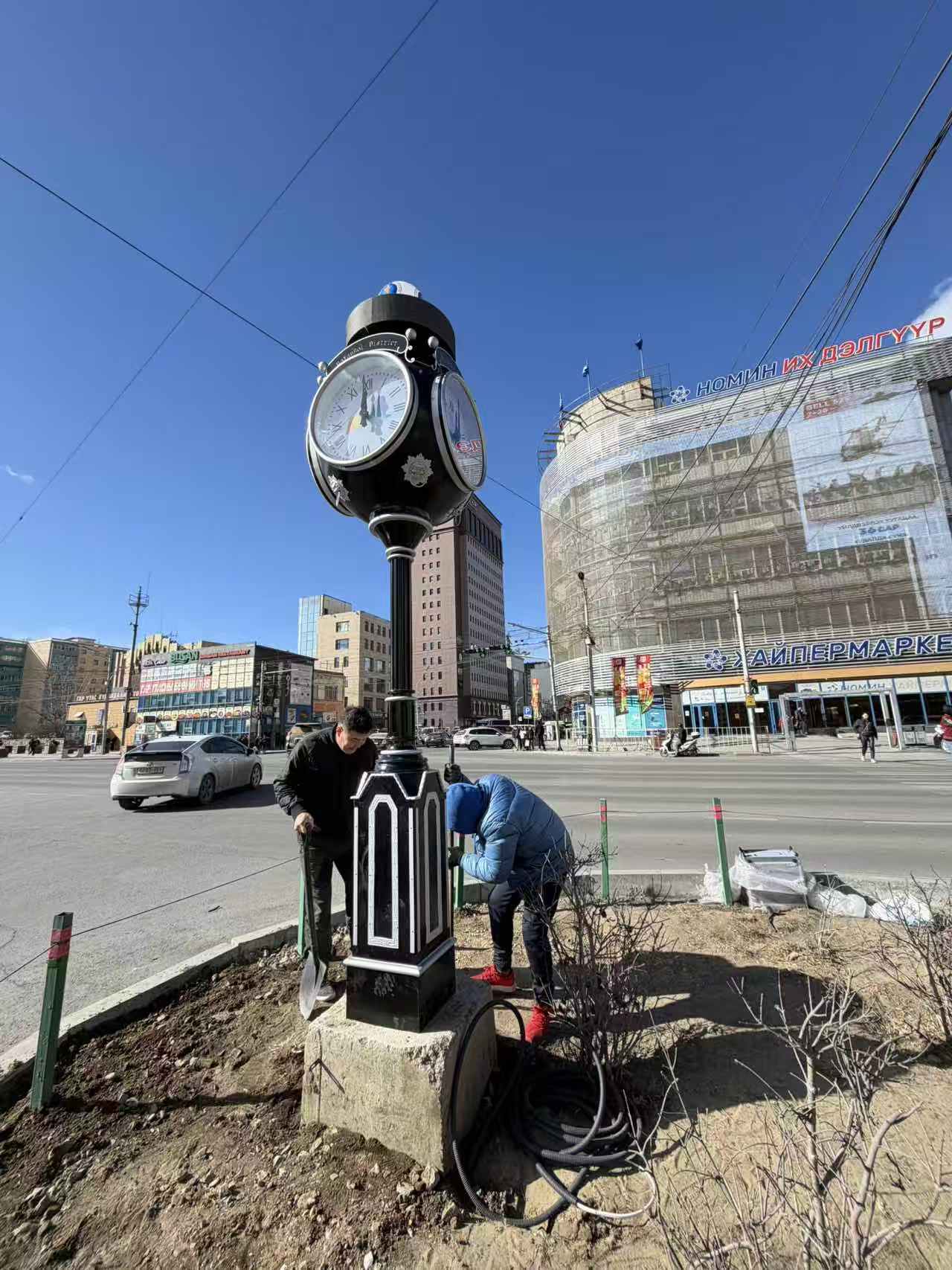 Multi-sided street clock installed in a busy city square.