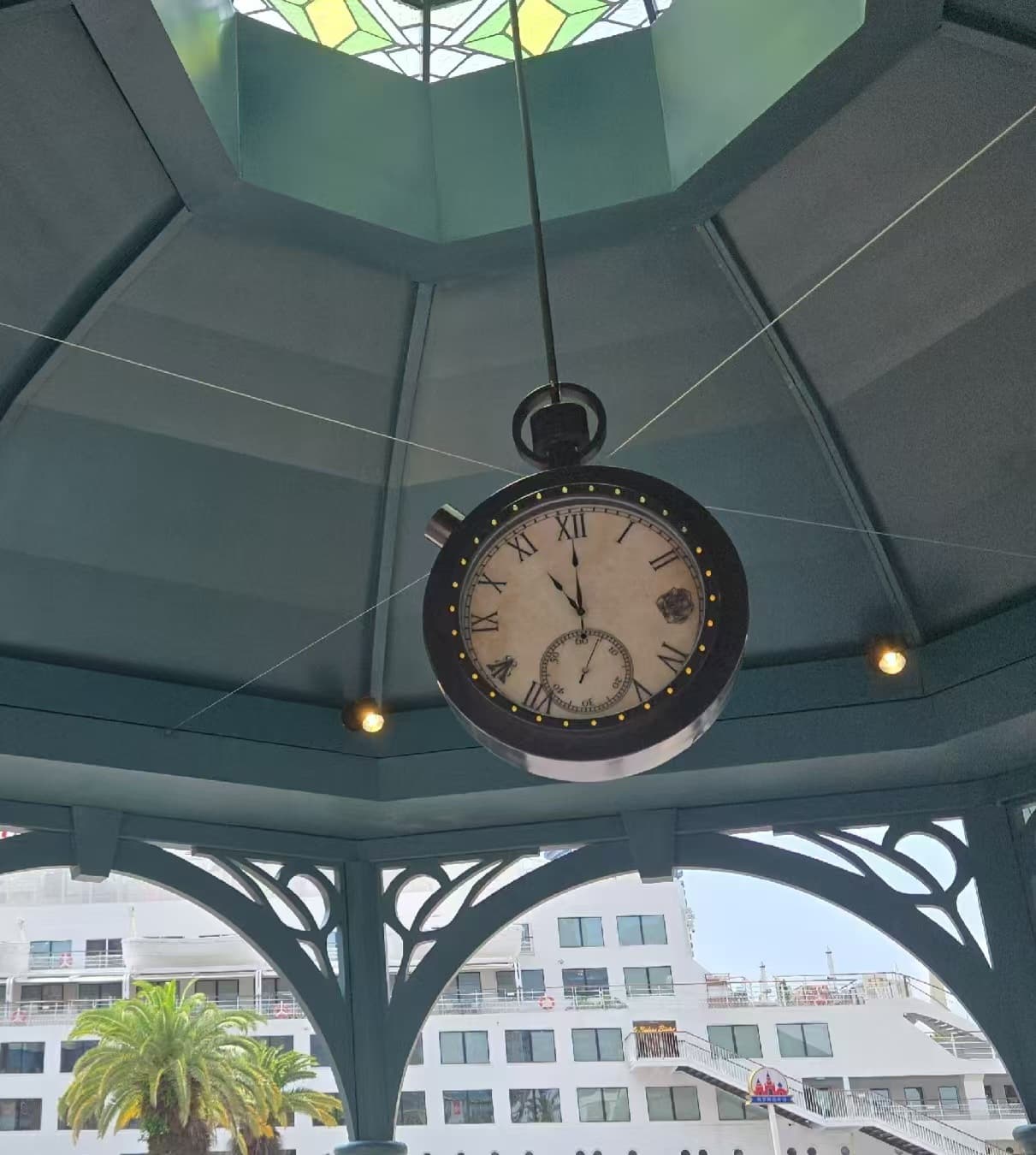 Suspended clock installed beneath a covered public pavilion.