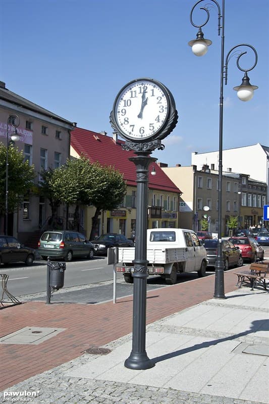 Freestanding street clock integrated into a city sidewalk.