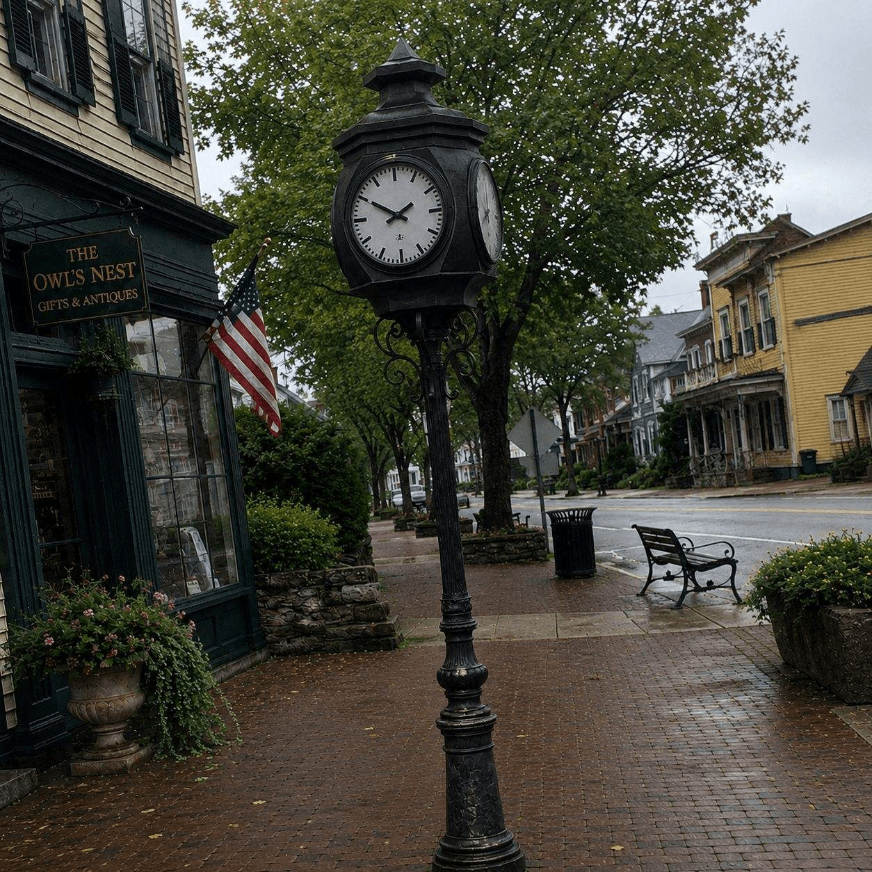 Black street clock installed along a tree-lined main street.