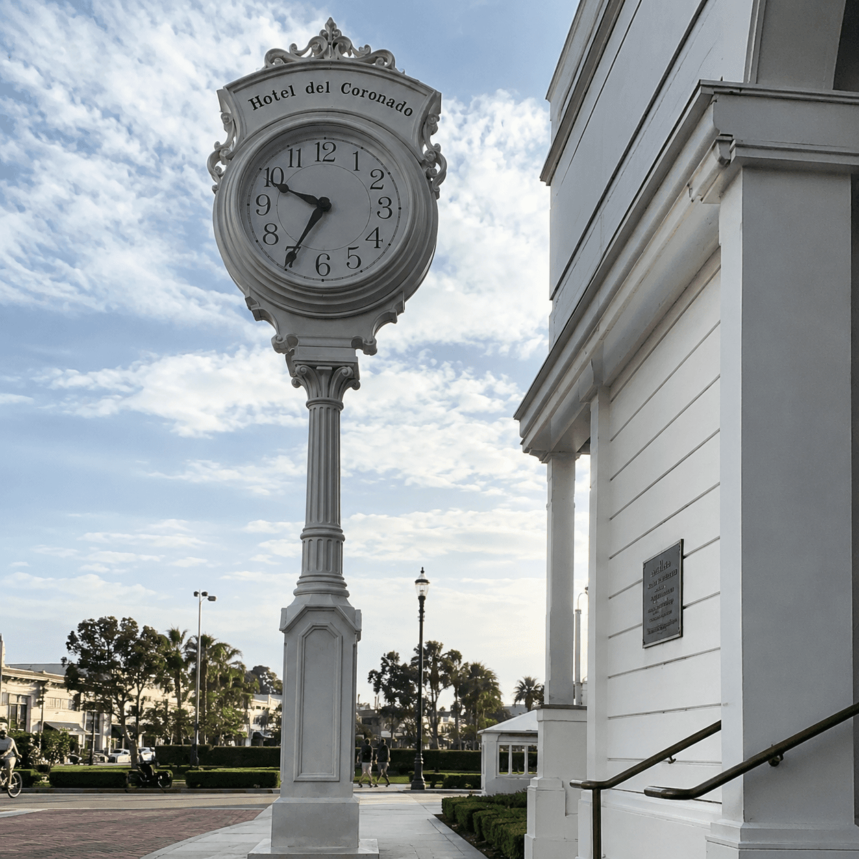 Ornate street clock beside a hotel promenade.