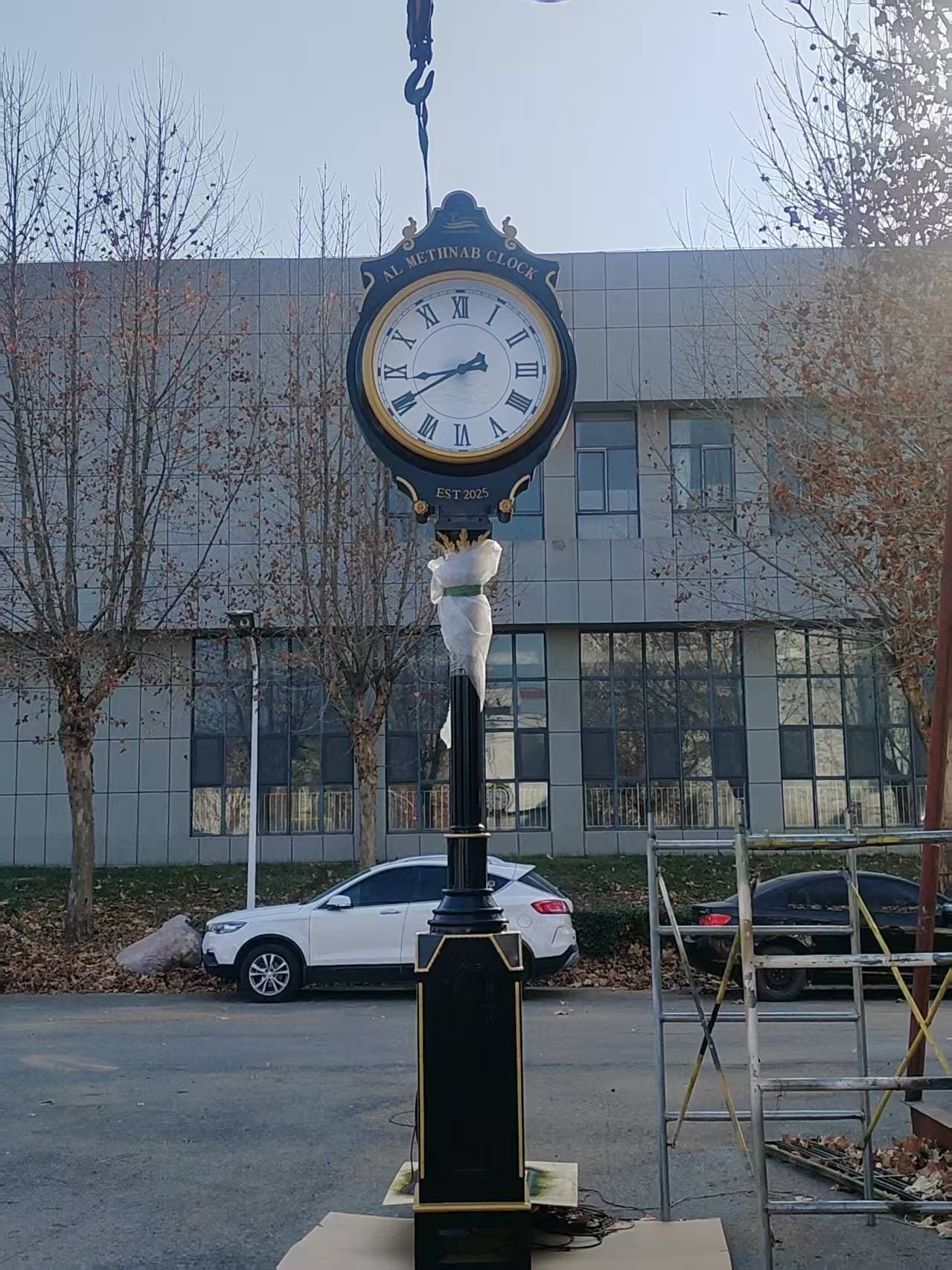 Black landscape clock lifted into position outside a facility.